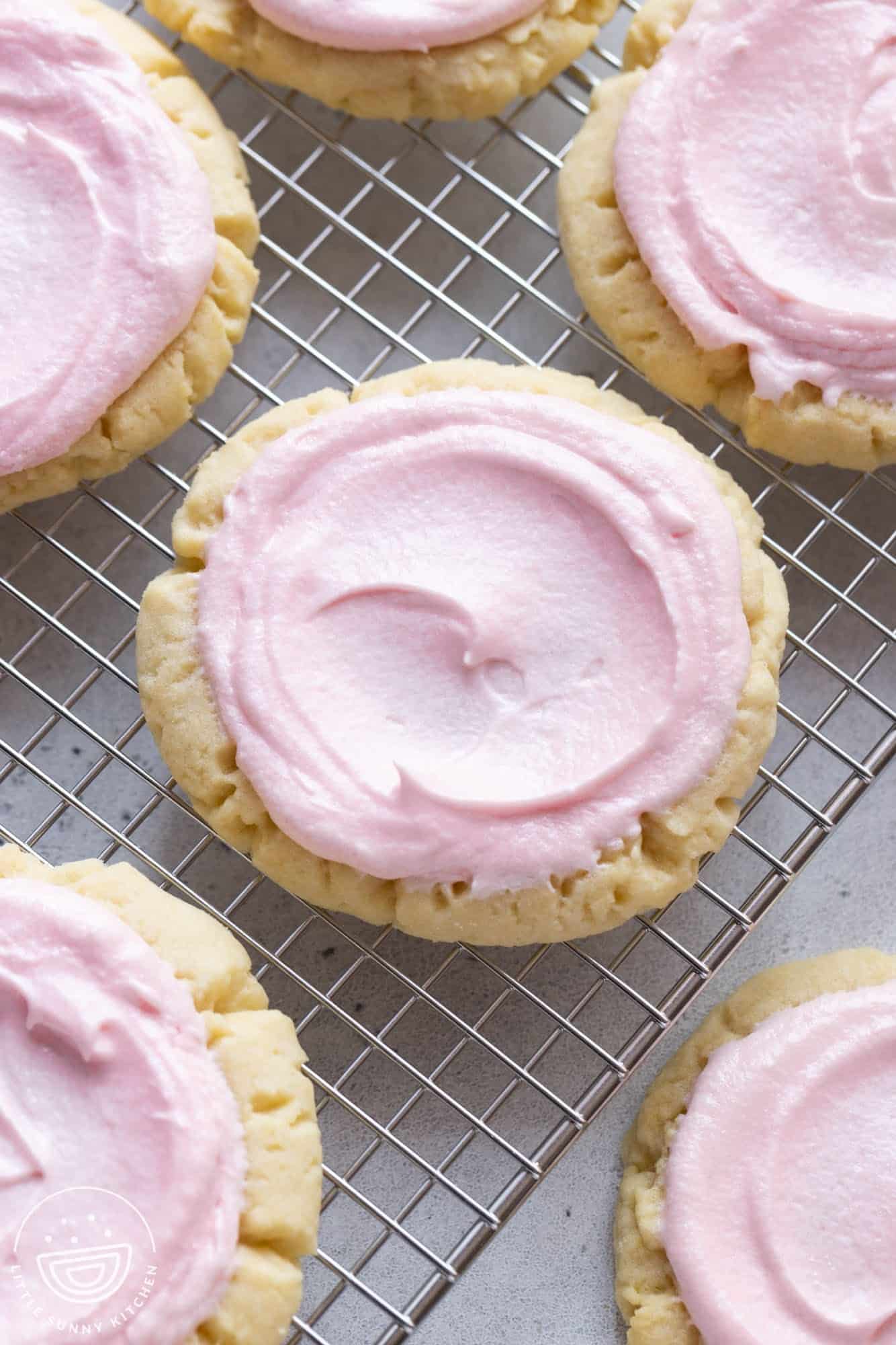sugar cookies like swig, with pink frosting, on a wire rack