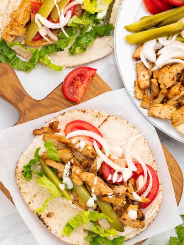 a pita on a cutting board, with chicken shawarma fillings on it.