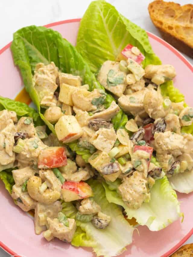 three romaine leaves on a plate, filled with curry chicken salad