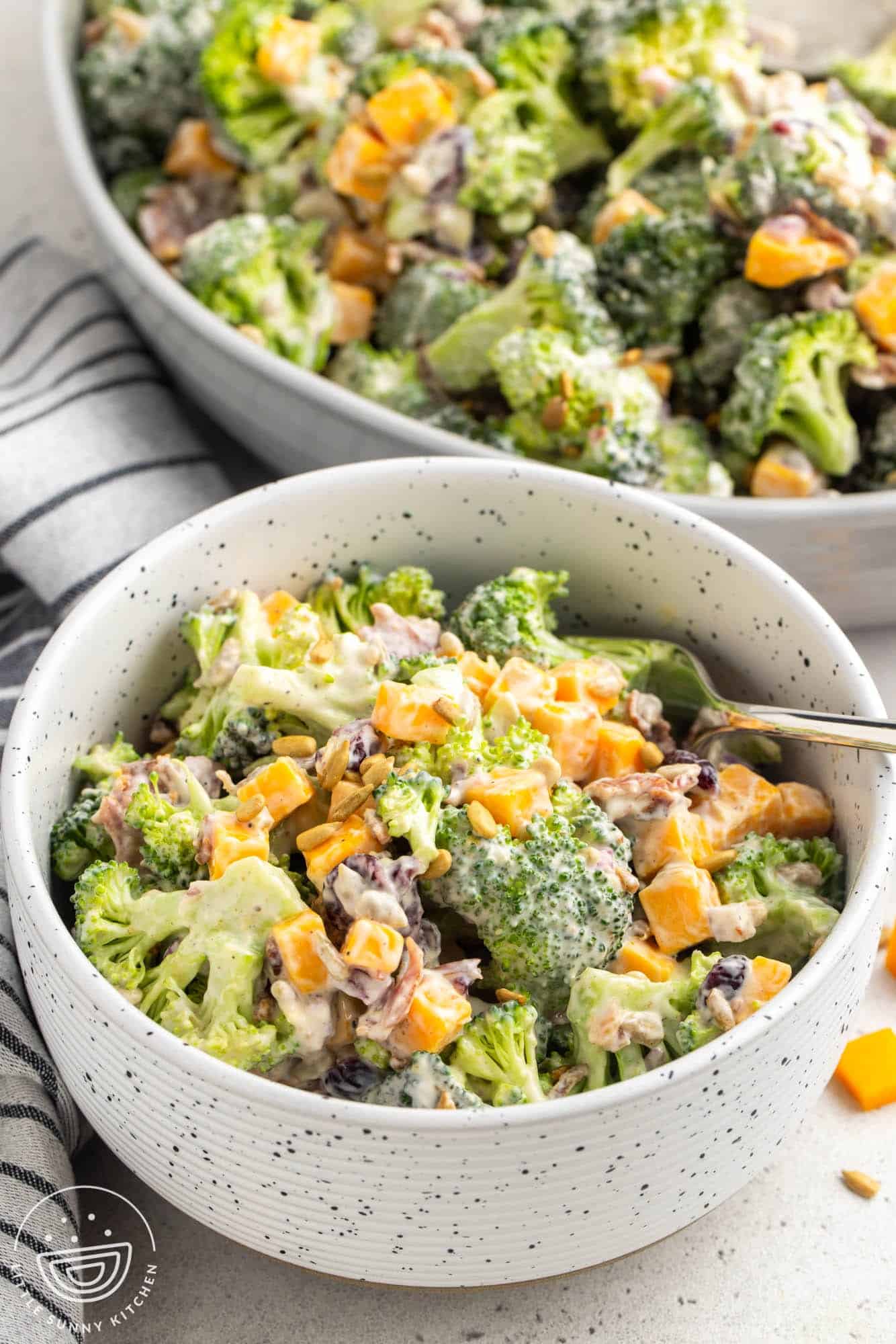 A small bowl of broccoli salad with cheese and a creamy dressing.