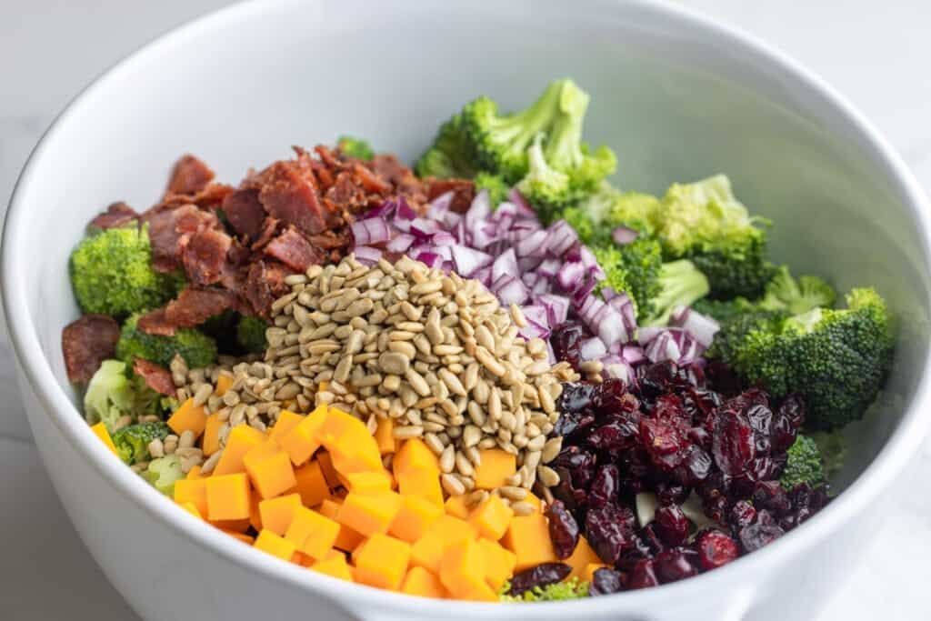 The ingredients for broccoli salad added to a bowl.