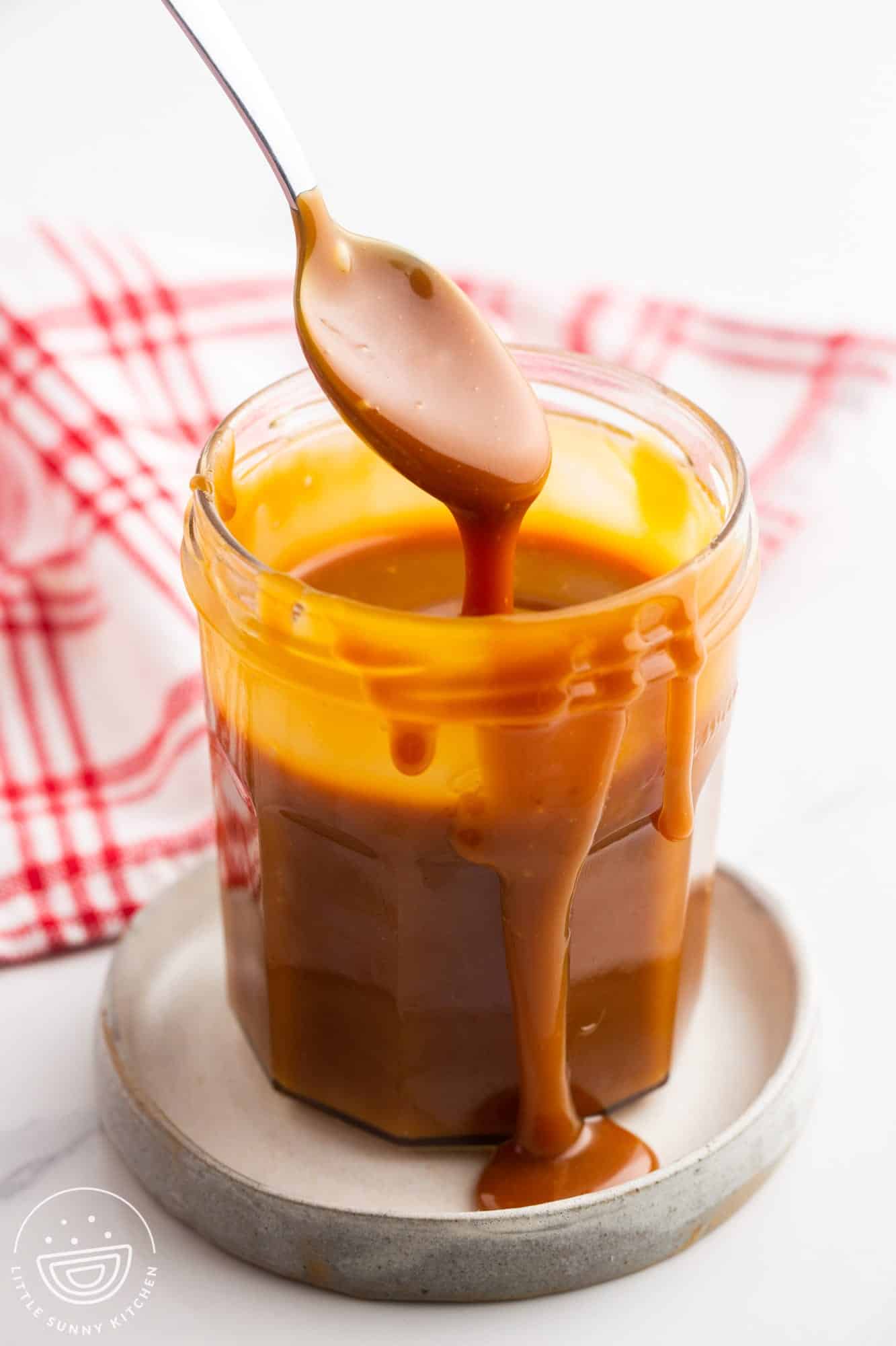 Caramel sauce in a jar with a spoon.