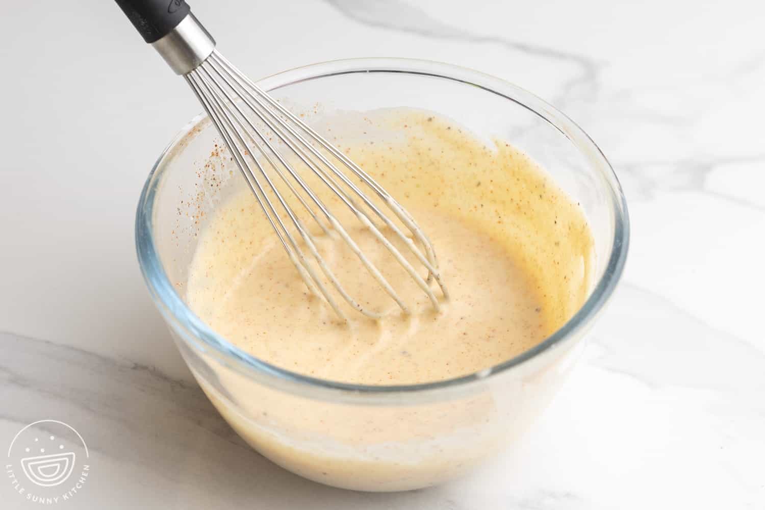 homemade chef salad dressing in a small glass bowl with a whisk.