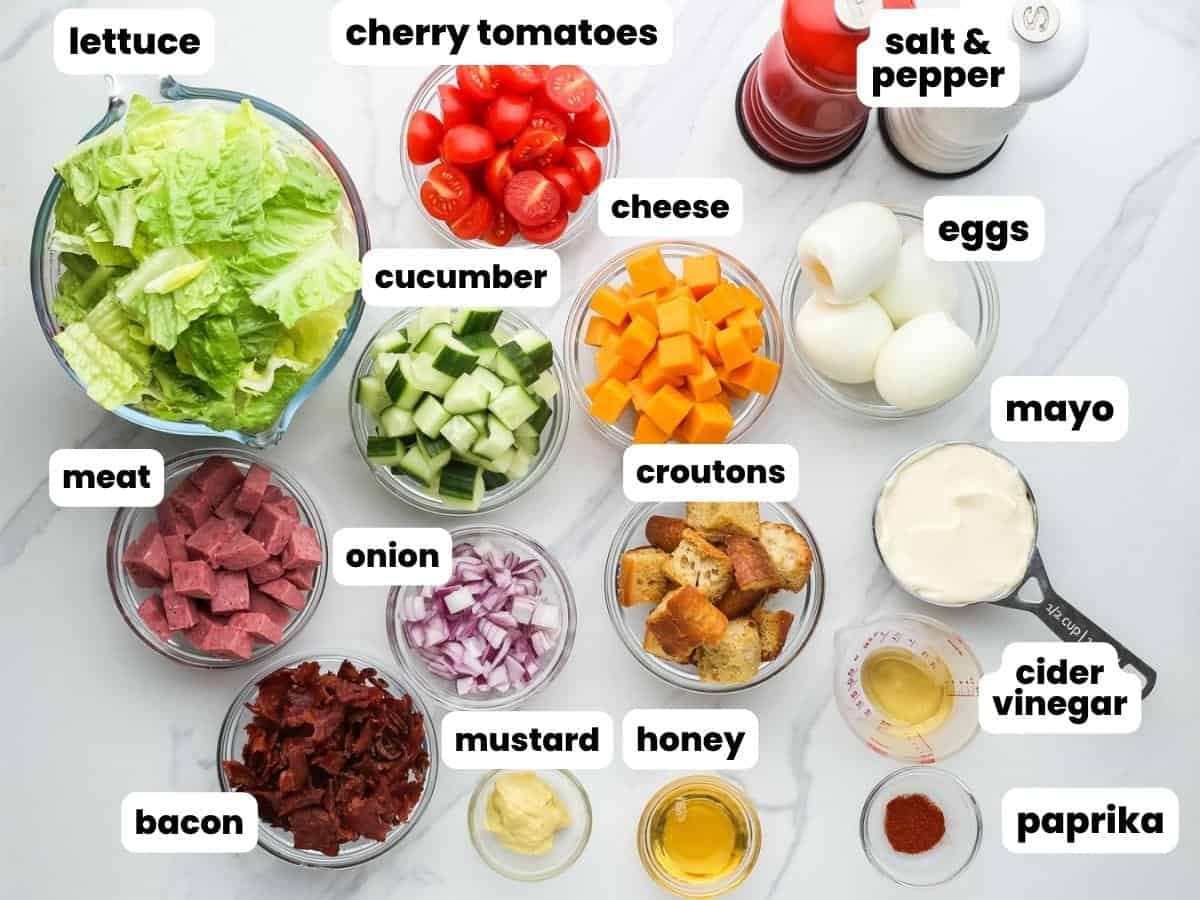 The ingredients for chef salad with eggs, meat, cheese, and veggies, all cut and in small bowls.