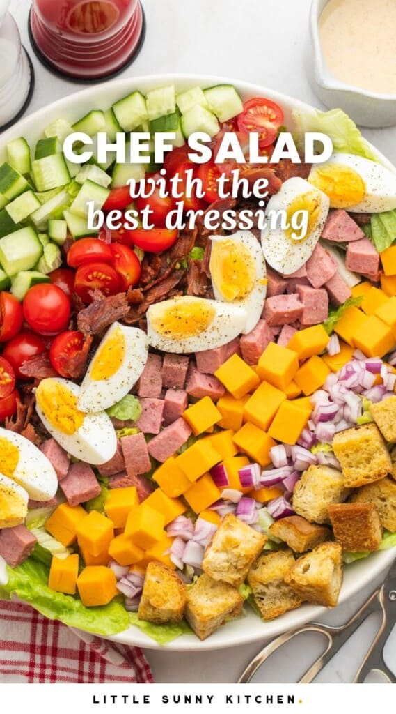 A large bowl of chef salad, layered with hard boiled eggs, meat, cheese, and croutons. Text overlay says "chef salad with the best dressing"