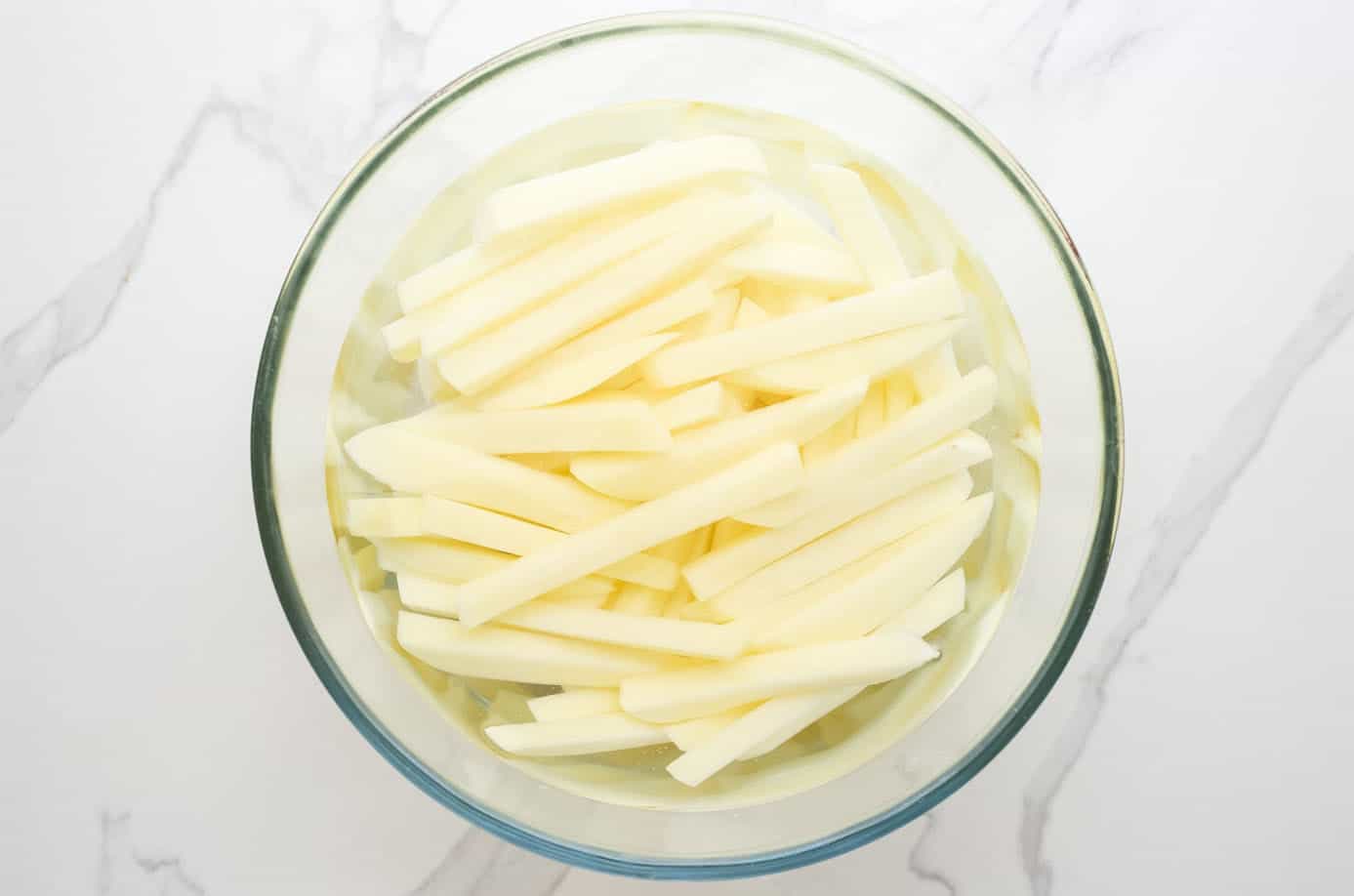 sliced potatoes for french fries in water.