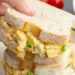 Two egg salad sandwiches on country white bread, stacked on top of one another.