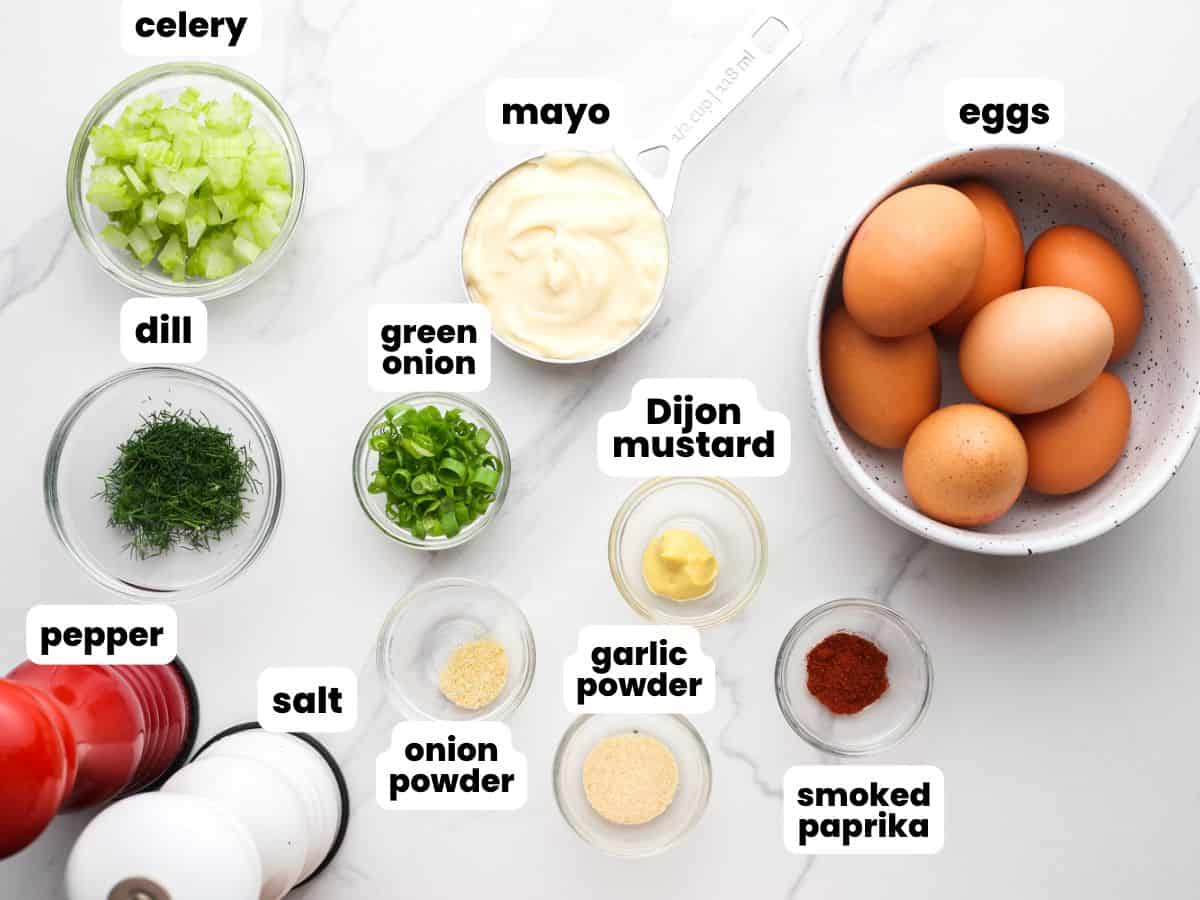 The ingredients needed to make the best egg salad, all in small bowls and arranged on a counter.