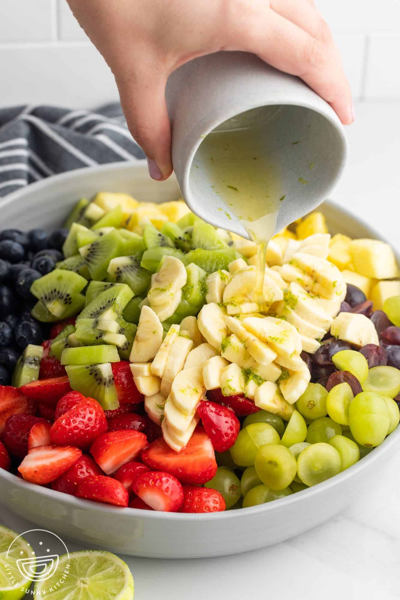 Adding the honey lime dressing to the fruit salad