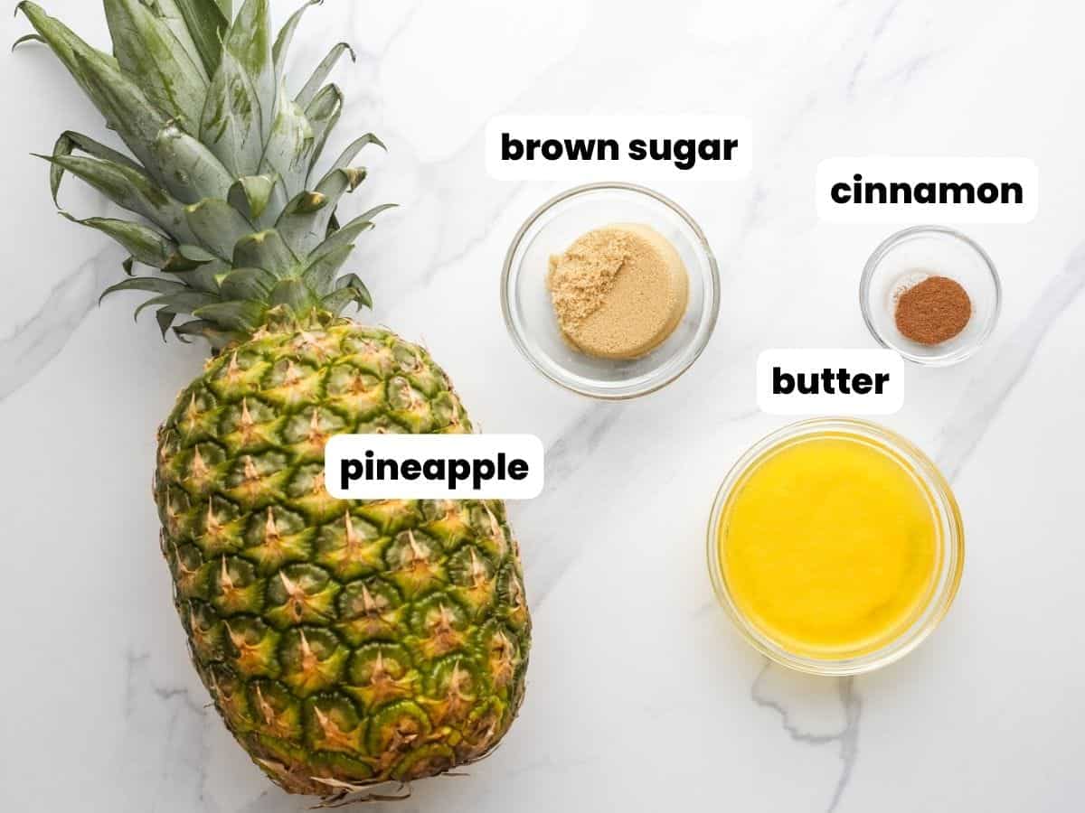 Ingredients needed to make grilled pineapple including a whole pineapple fruit, melted butter, brown sugar, and cinnamon.