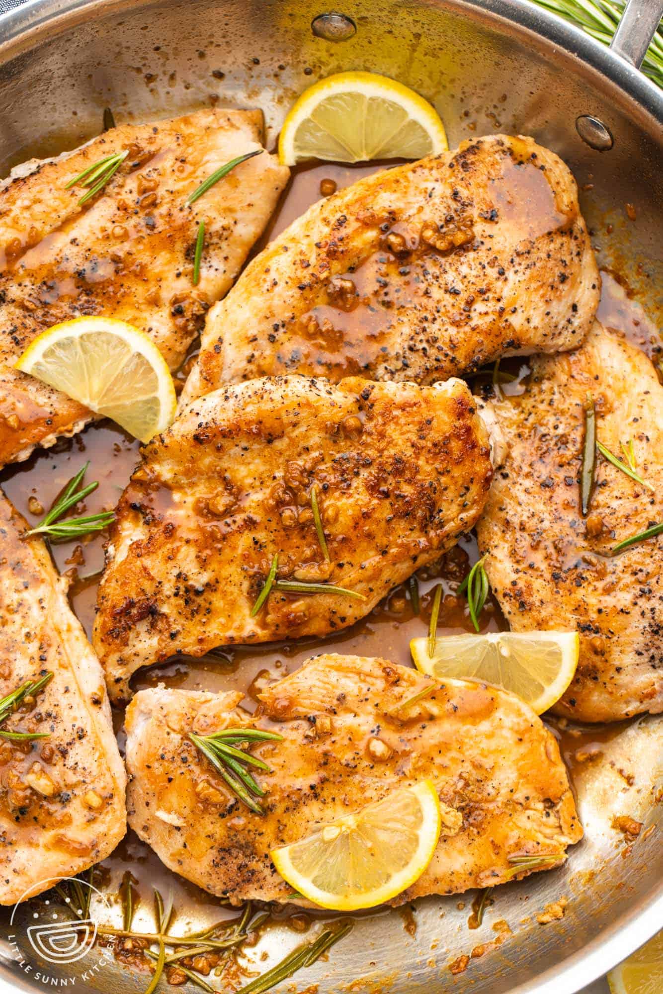 a stainless steel skillet with rosemary lemon chicken cutlets. 