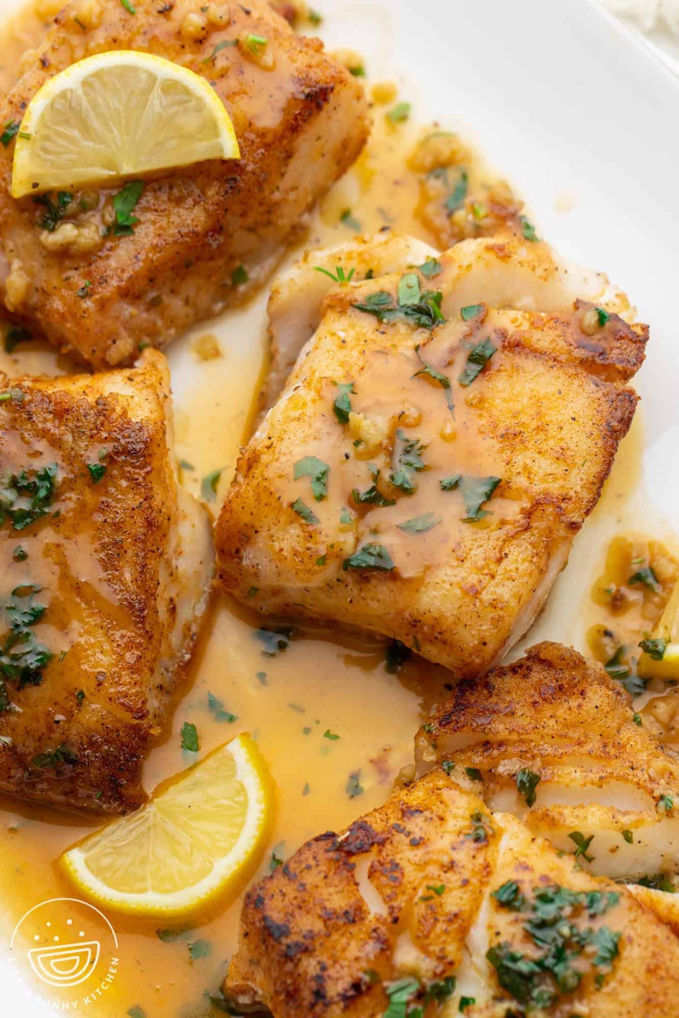 a platter of browned, seared cod fillets with a luscious lemon butter sauce.