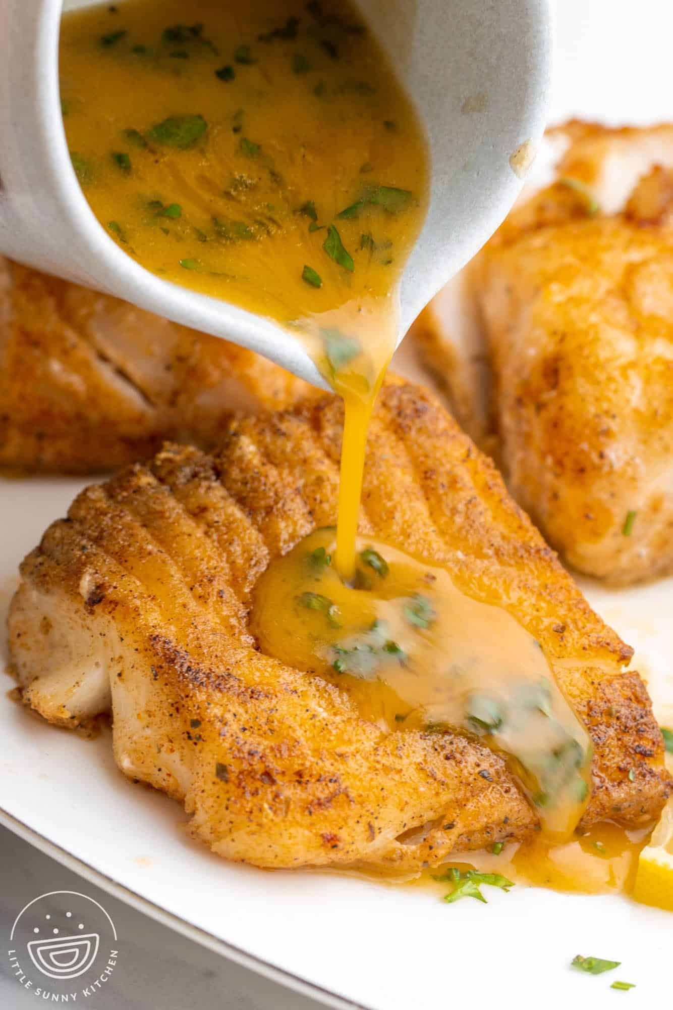 lemon butter sauce poured over pan seared cod fillets.
