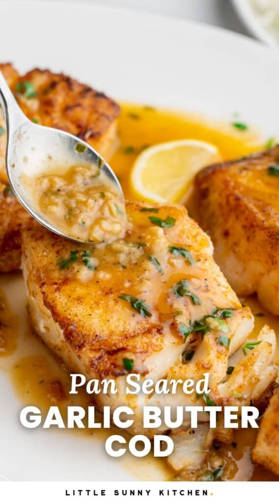 seared cod fillets. A spoon is added lemon garlic butter sauce to them. Text overlay says "pan seared garlic butter cod"