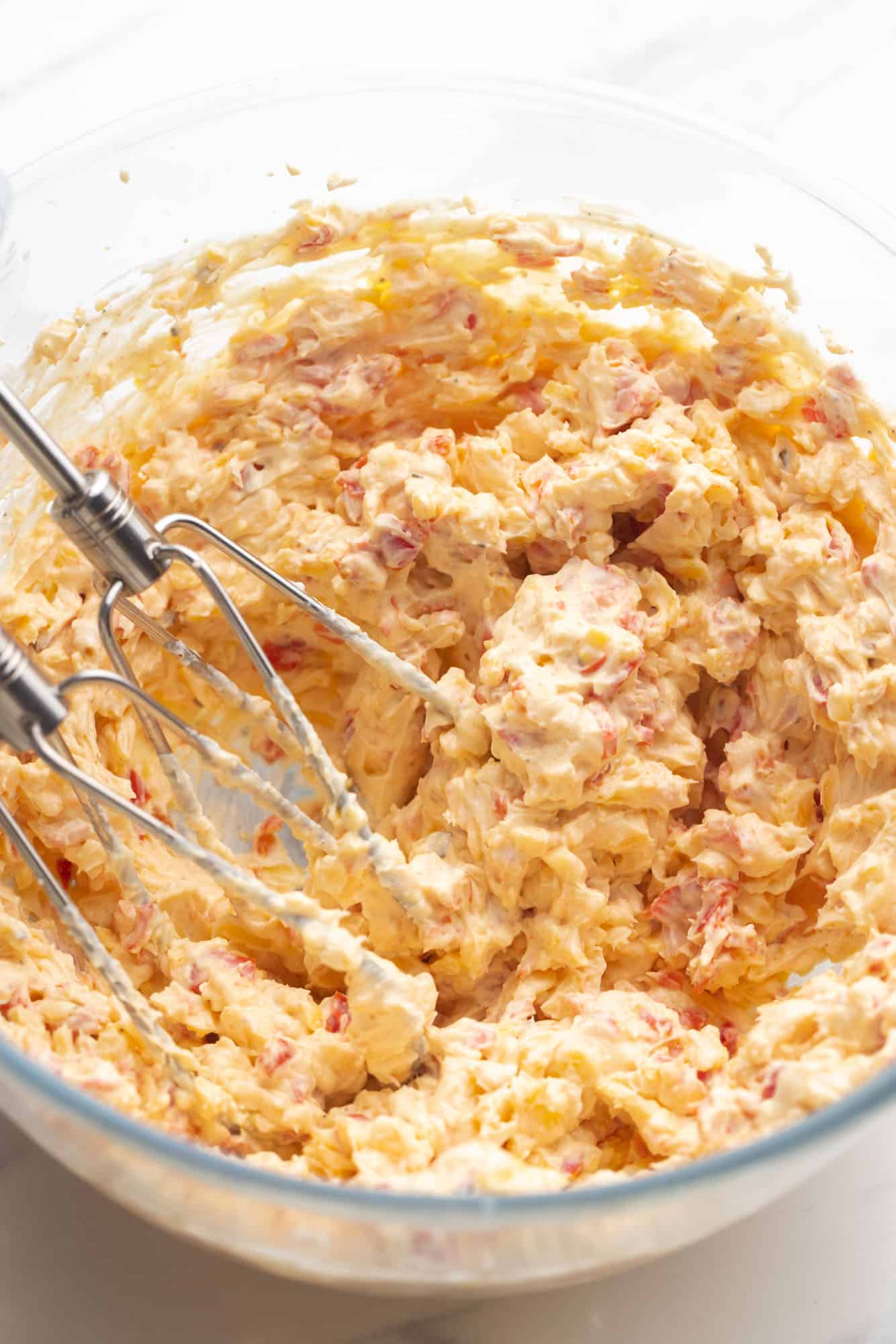 pimento cheese being mixed with an electric mixer.