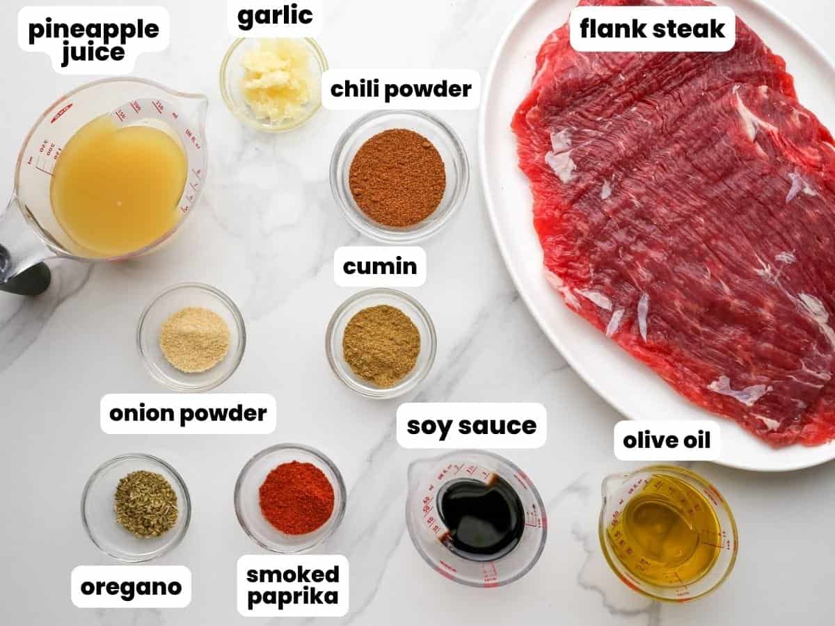 The ingredients needed to make steak fajitas, including a flank steak, pineapple juice, and spices.