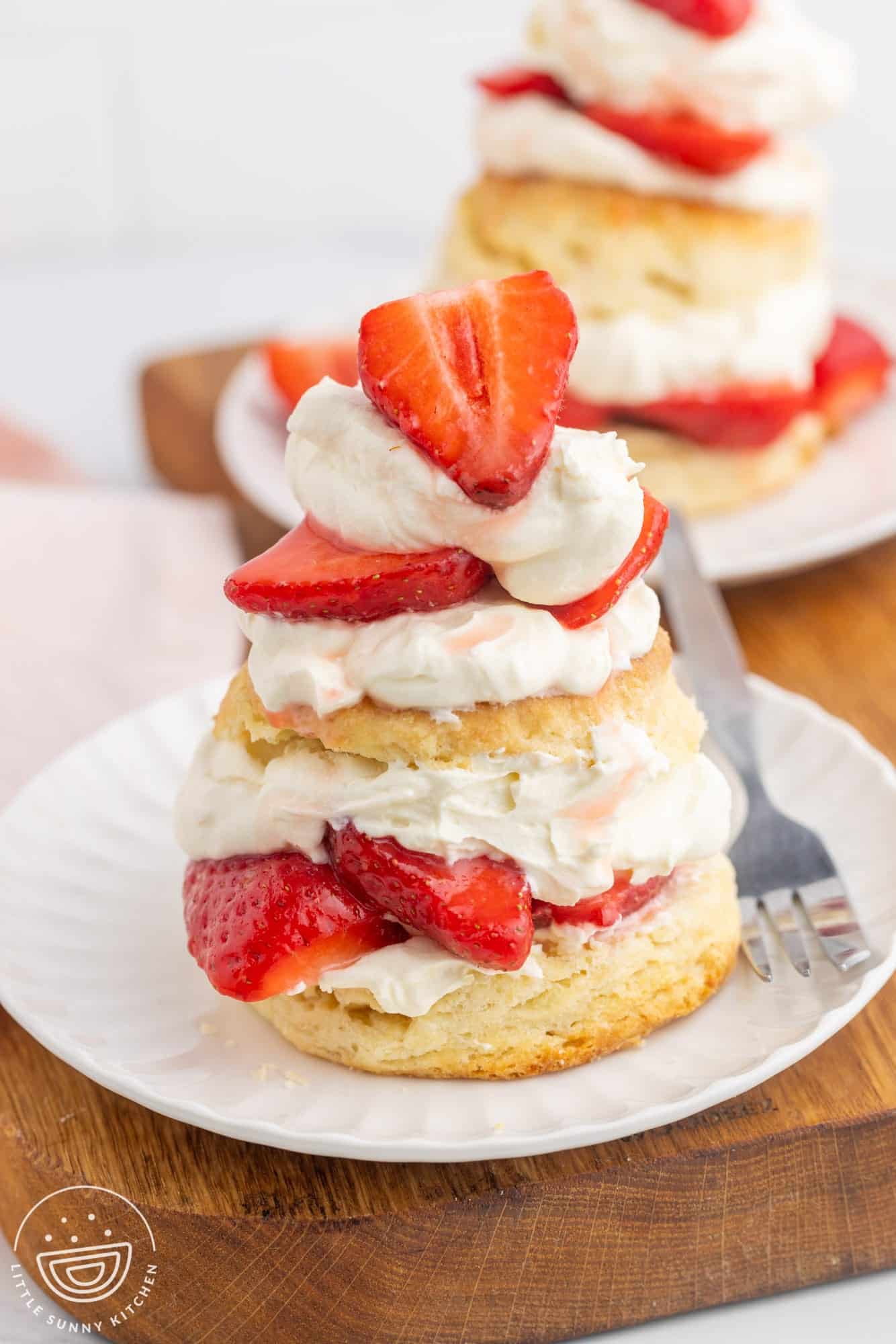Strawberry shortcake on a small white plate and a fork on the side