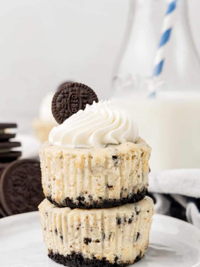 Two mini cheesecakes stacked on each other. There is a bottle of milk in the background
