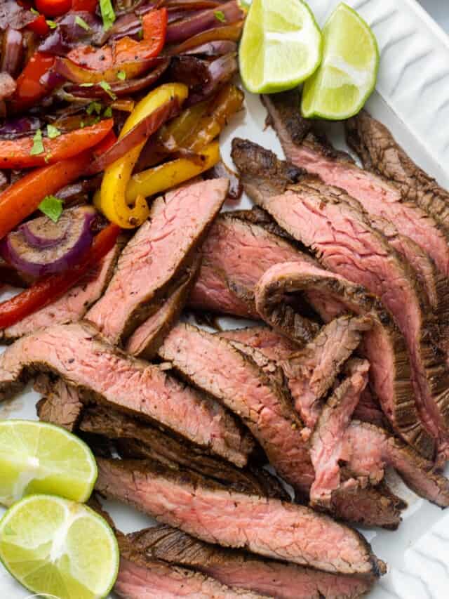 a platter of sliced steak fajitas with veggies