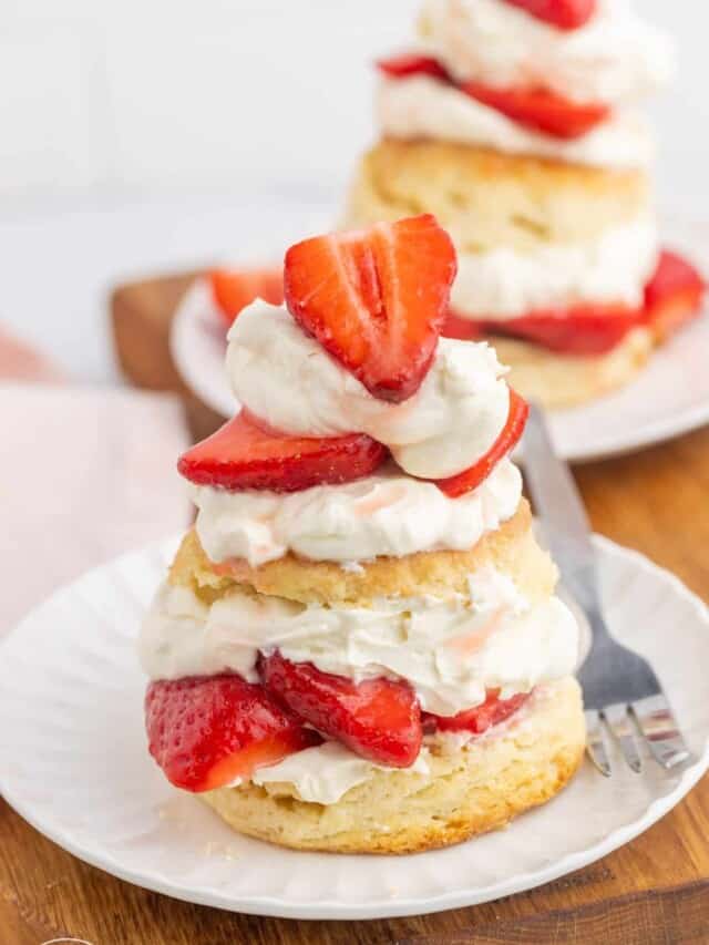 Strawberry shortcake on a small white plate and a fork on the side