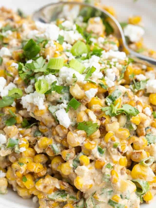a bowl of creamy mexican street corn salad with cheese and cilantro.
