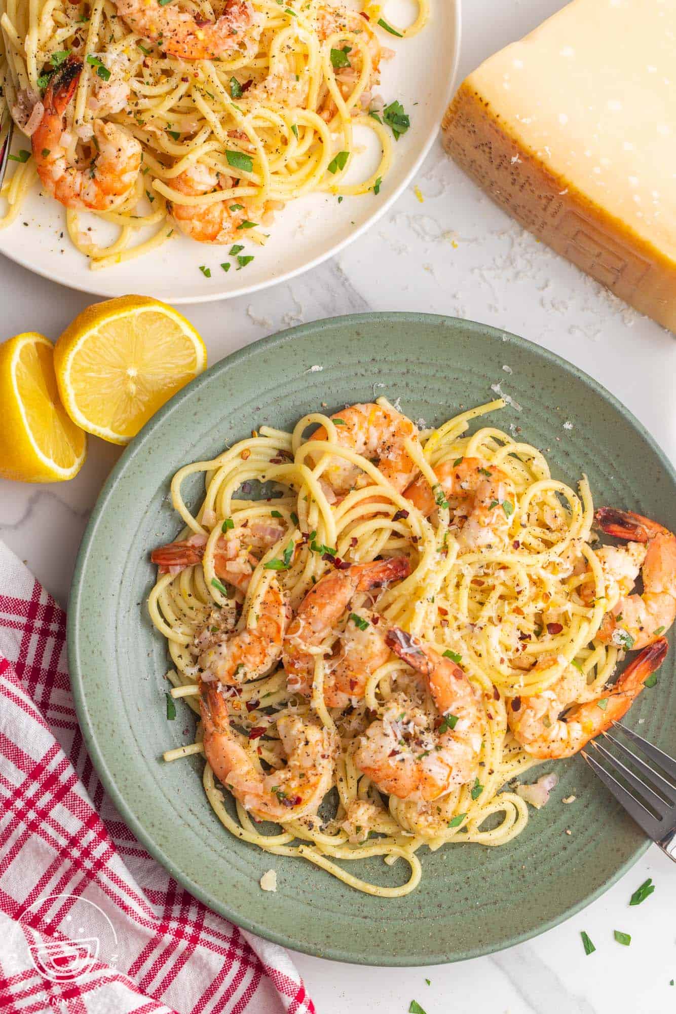a green plate with a serving of spaghetti and baked shrimp scampi.
