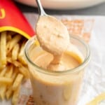 Copycat Big Mac sauce in a jar with a spoon, with fries and a salad in the background