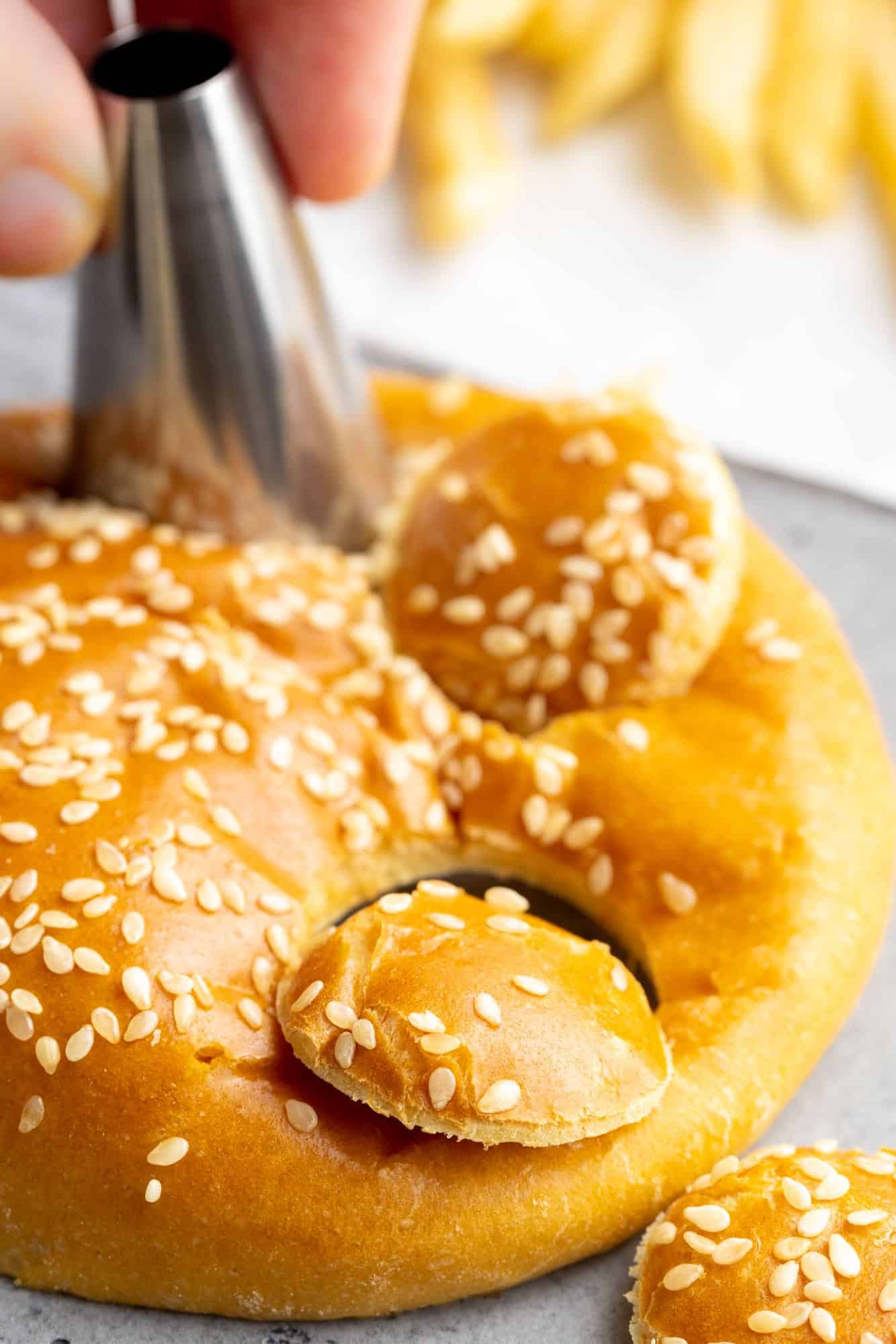 a large round piping tip punching circles from a sesame seed bun.