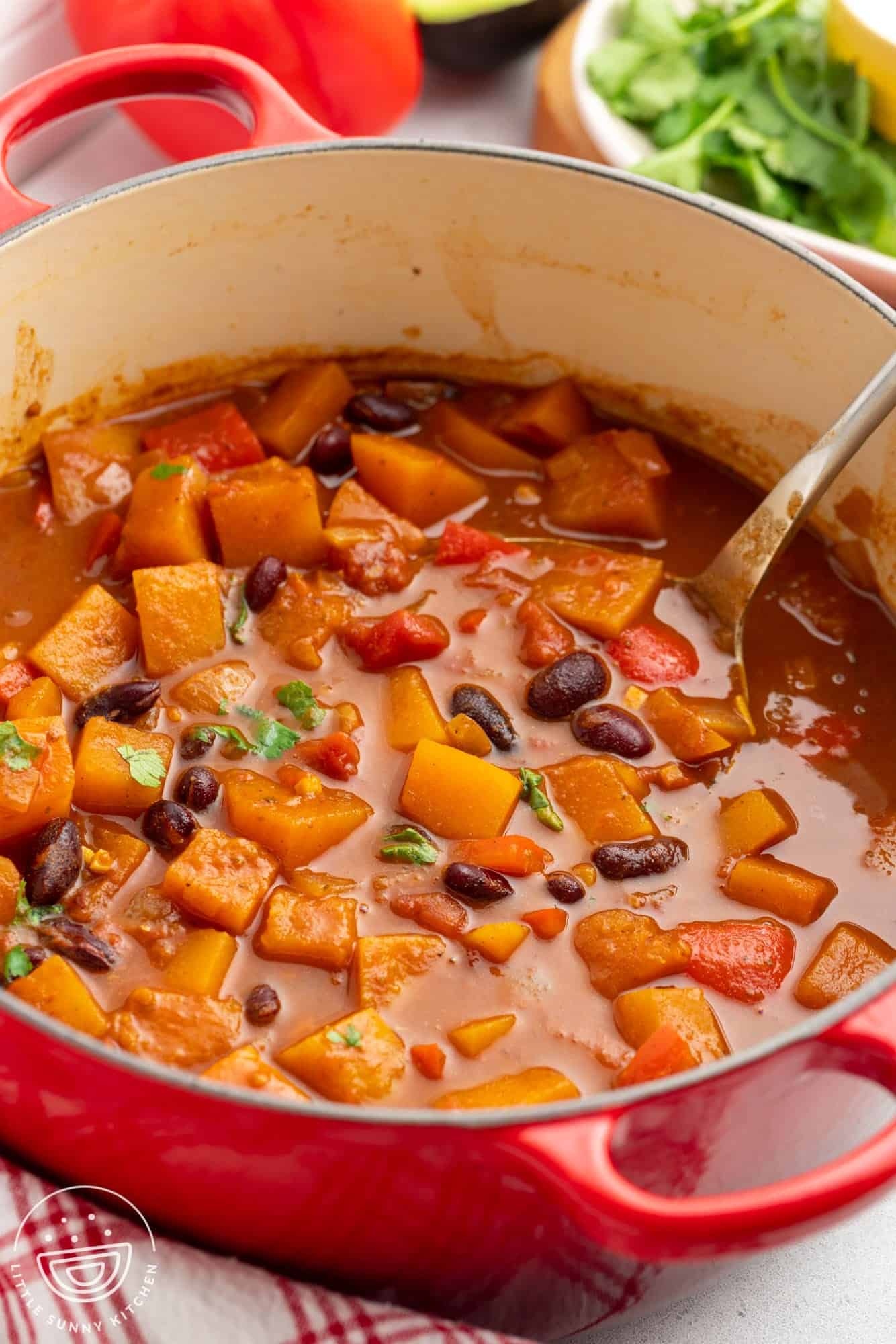 a red dutch oven filled with butternut squash chili