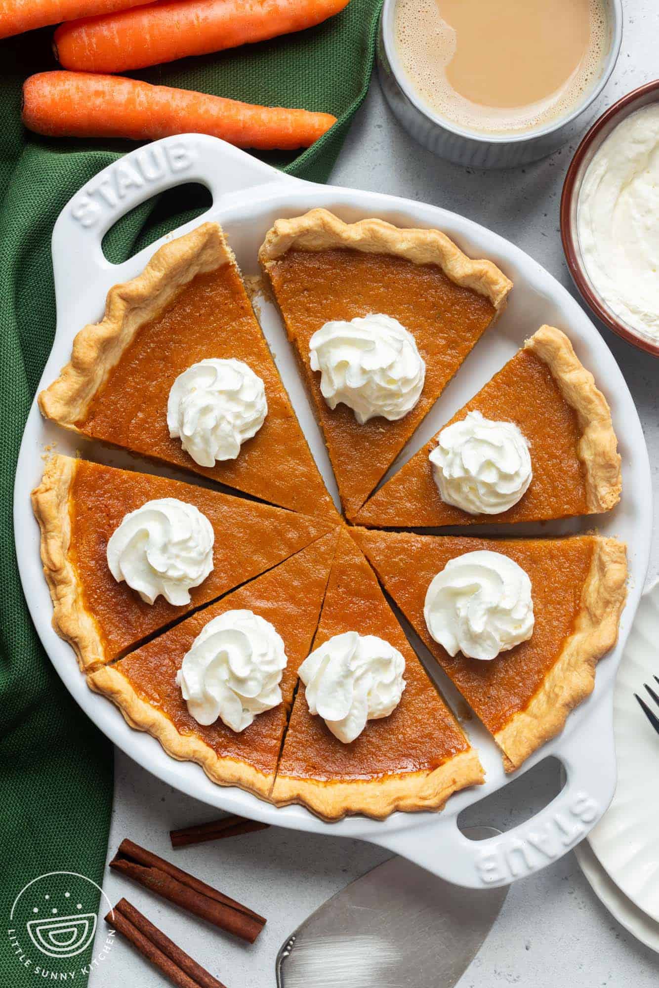 top down view of a homemade carrot pie cut into 8 slices, topped with whipped cream.