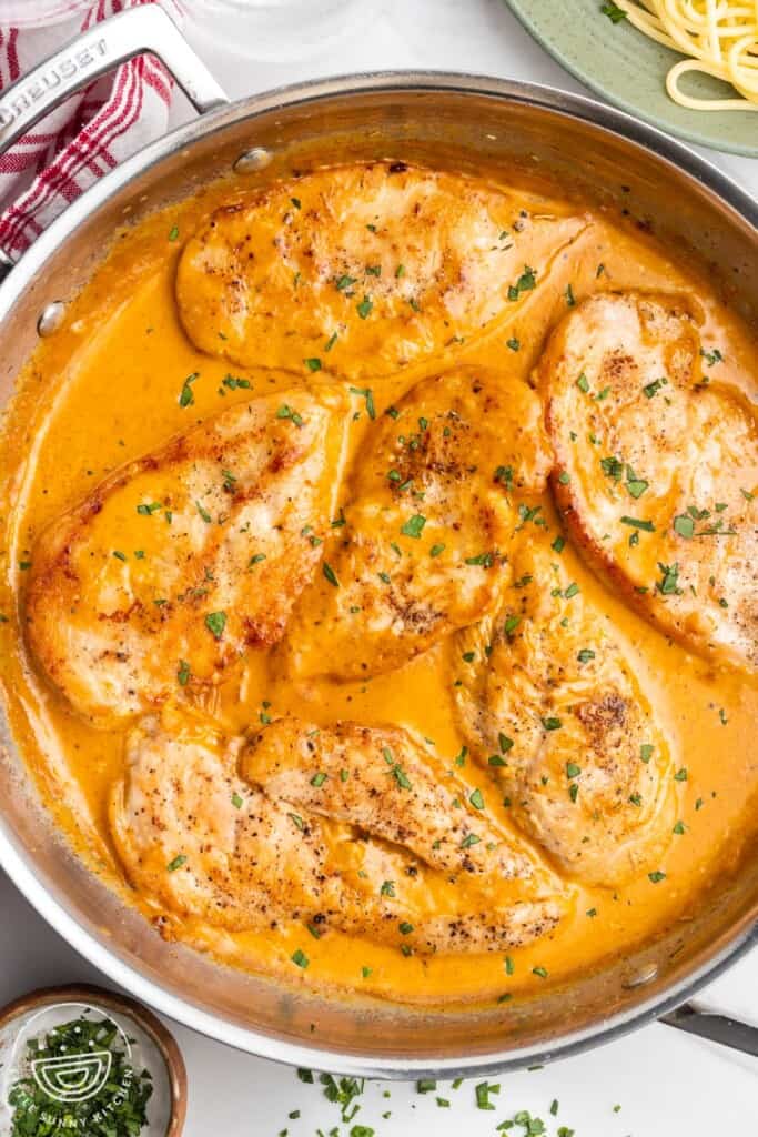 A stainless steel skillet of chicken in a flavorful creamy sauce