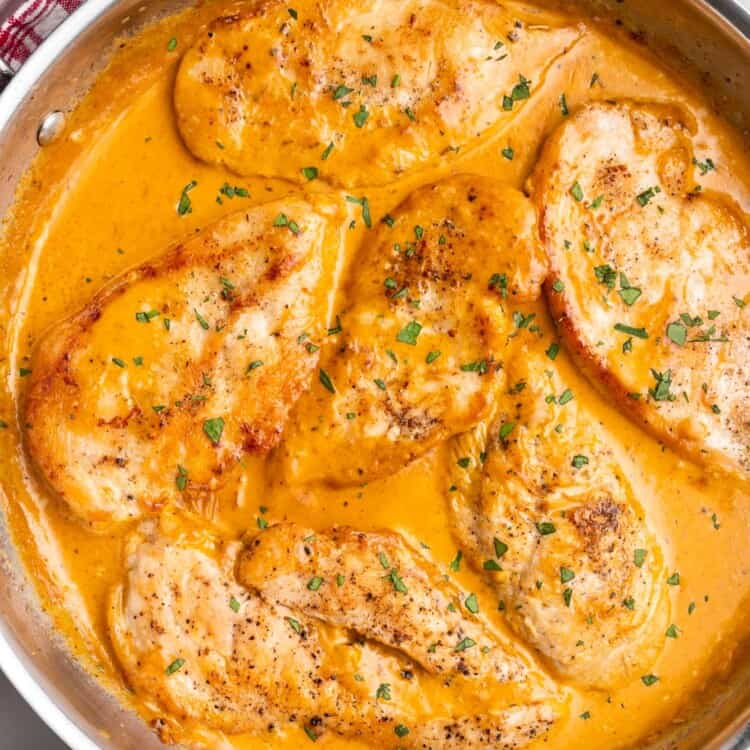A stainless steel skillet of chicken in a flavorful creamy sauce
