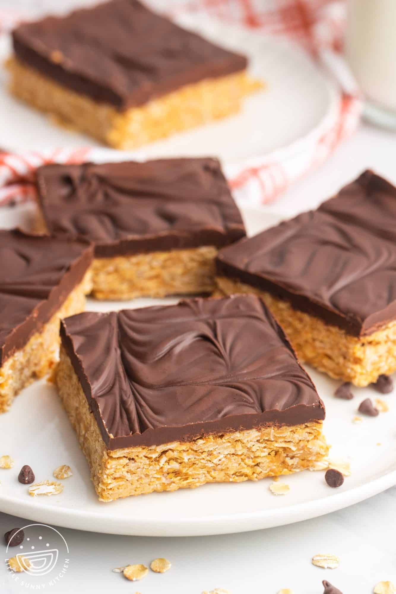 a plate holding four square oatmeal bars with chocolate topping.