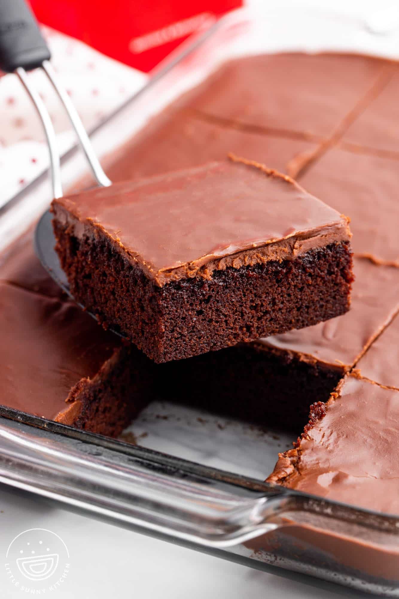 a spatula lifting a square slice of homemade coca cola cake out of a pan