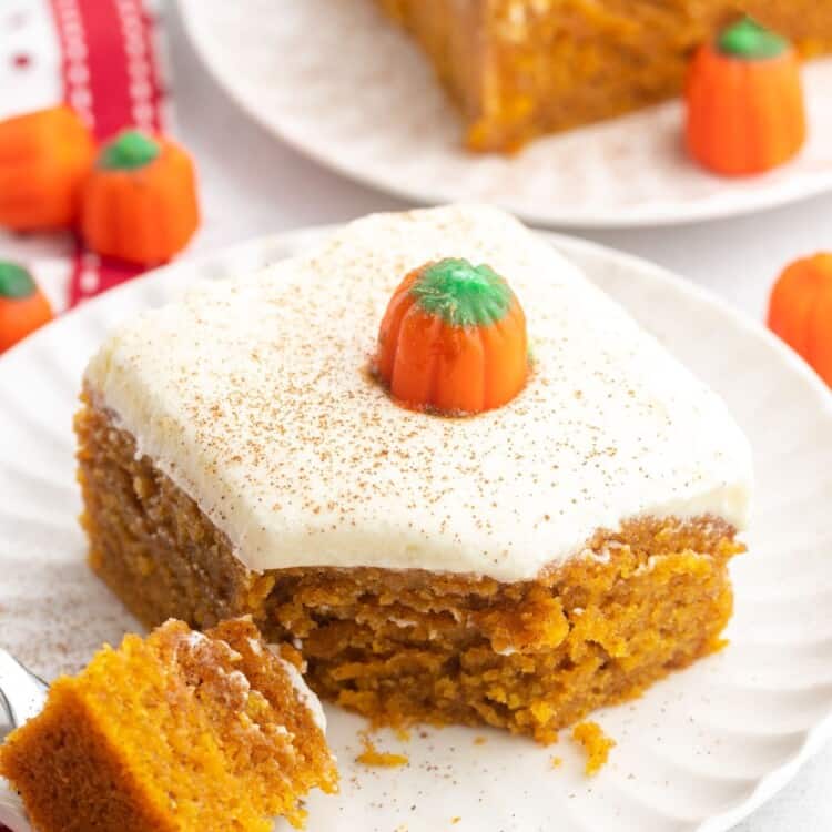 a square piece of pumpkin cake with frosting on a dessert plate.
