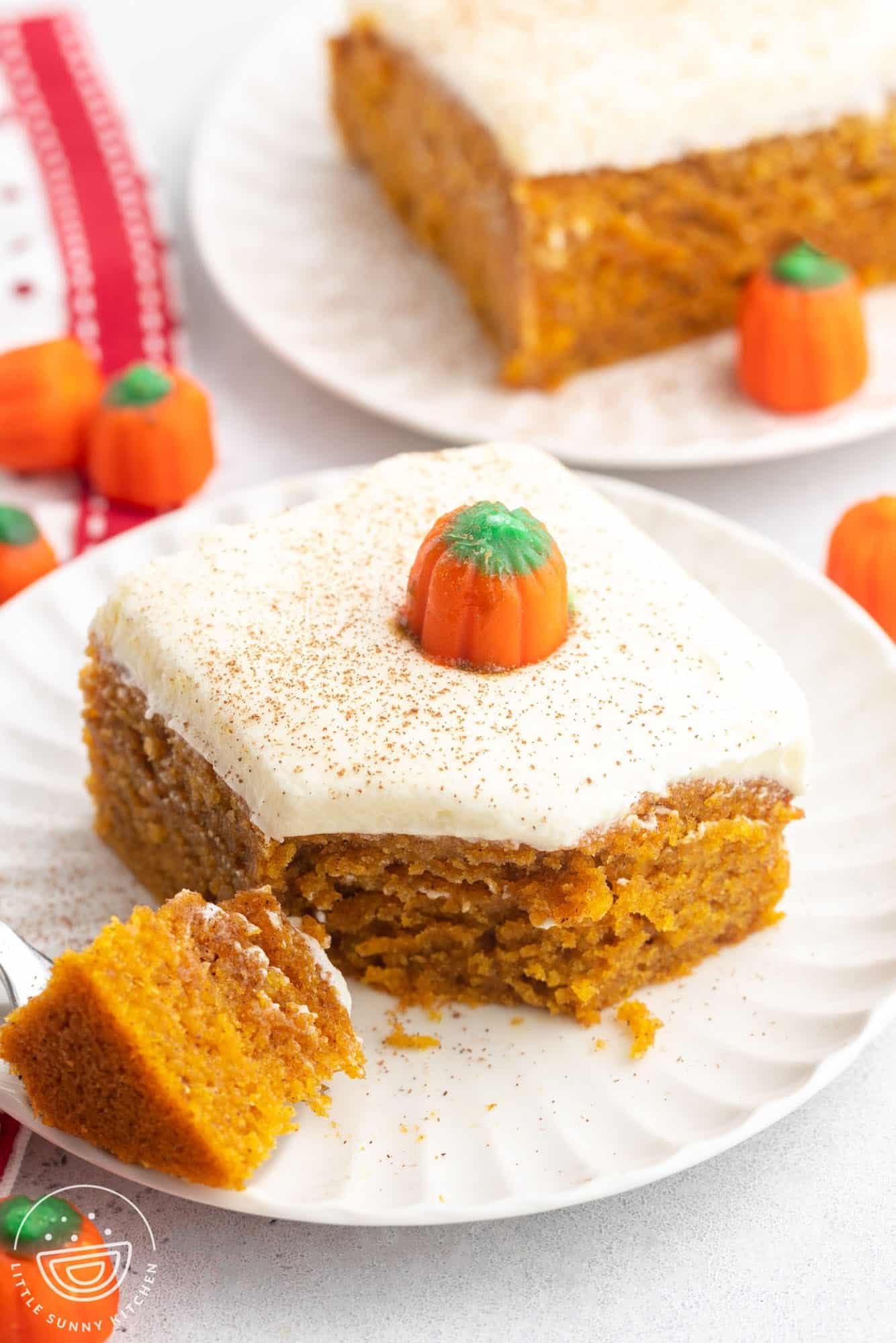 a square piece of pumpkin cake with frosting on a dessert plate.