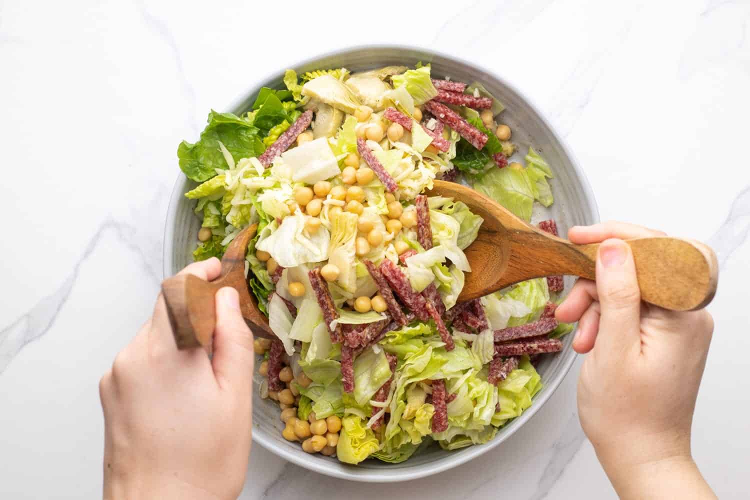 Tossing the salad with wooden spoons