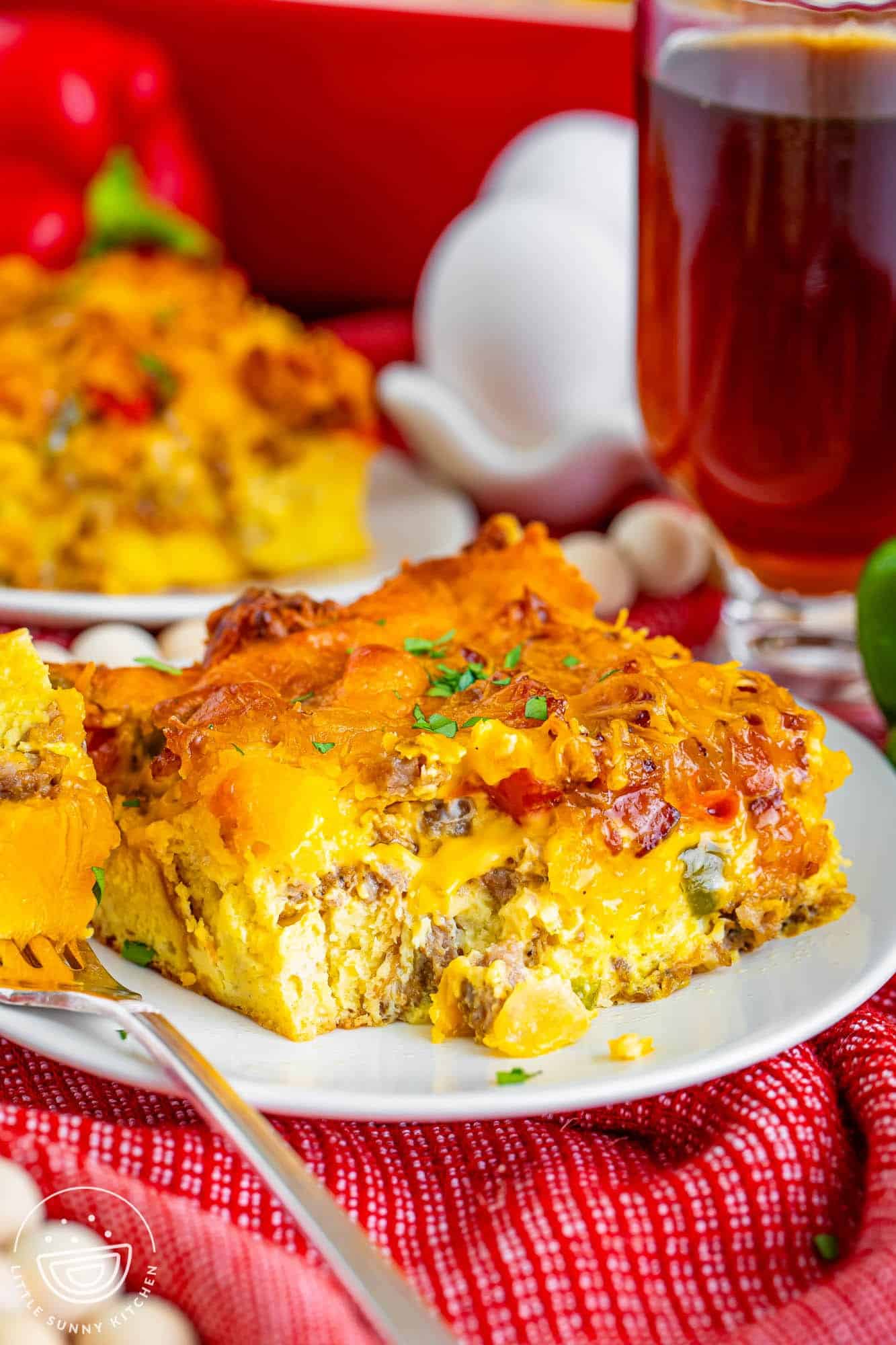 a piece of breakfast casserole and a mug of tea. a fork has taken a bite of the meal.