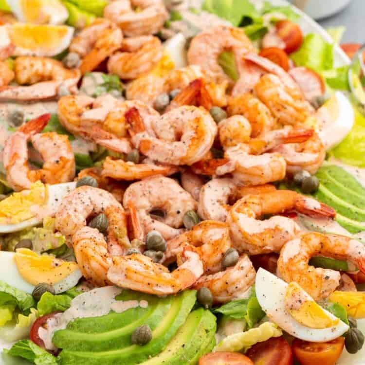 Shrimp Louie Salad is a large platter of salad with shrimp, capers, homemade dressing, egg, and avocado.
