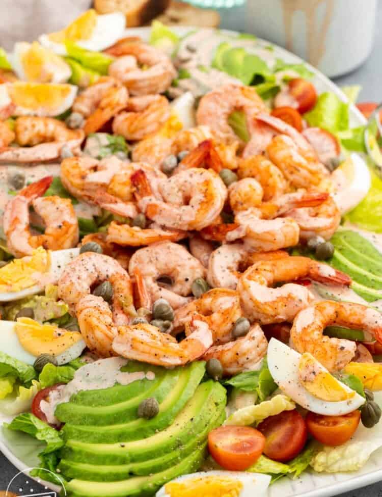 Shrimp Louie Salad is a large platter of salad with shrimp, capers, homemade dressing, egg, and avocado.
