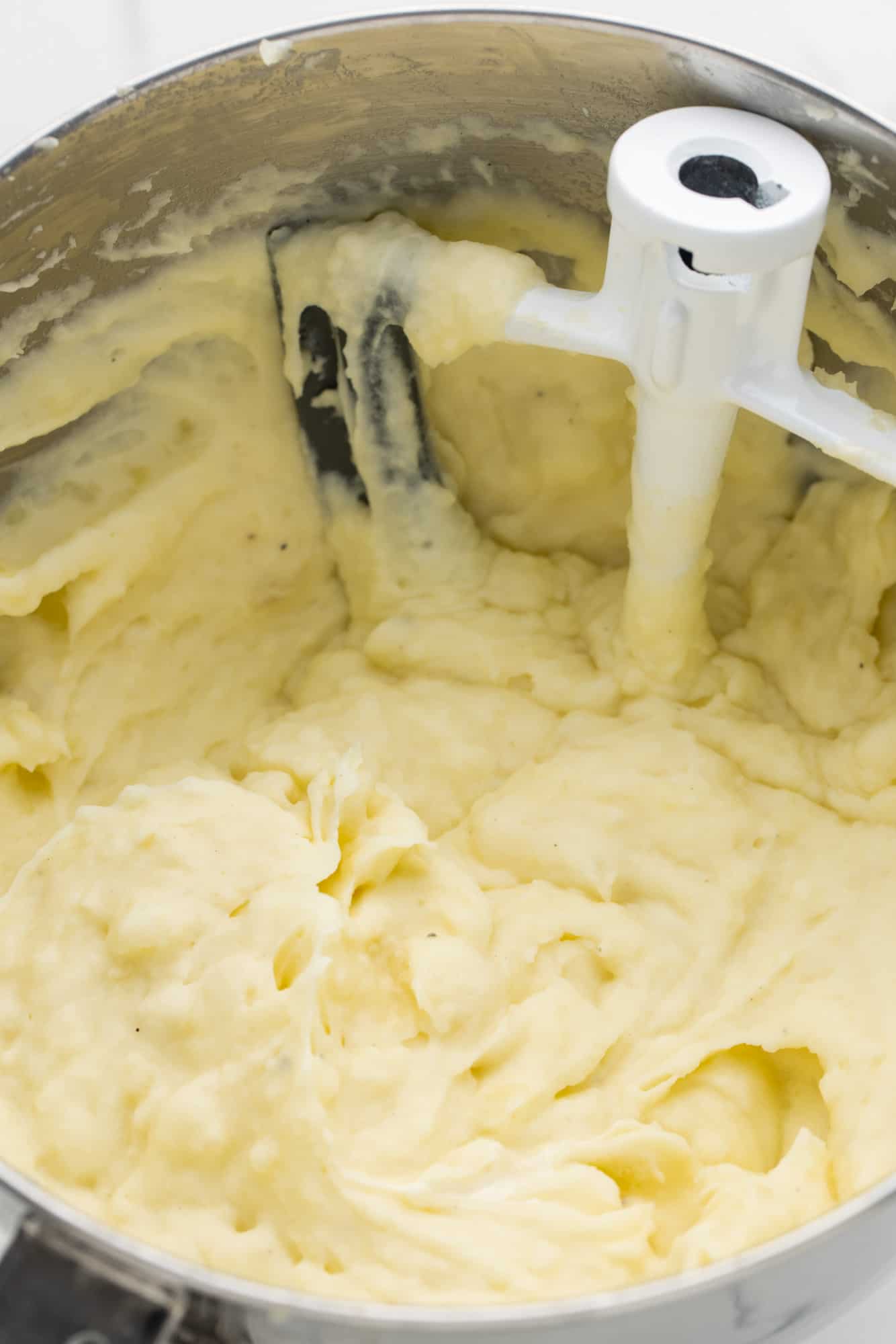 Whipped mashed potatoes in a mixer bowl with a paddle attachment