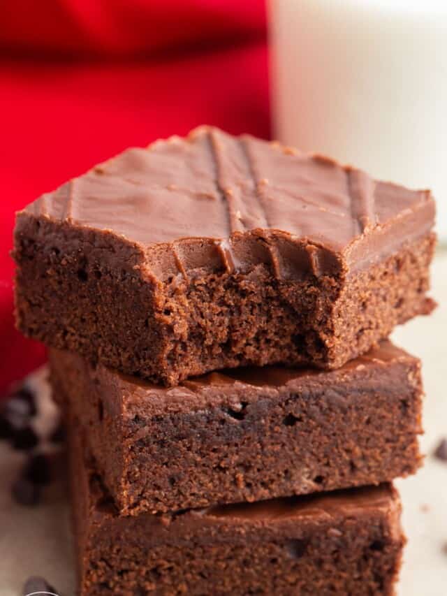 a stack of three lunch lady brownies with chocolate frosting.