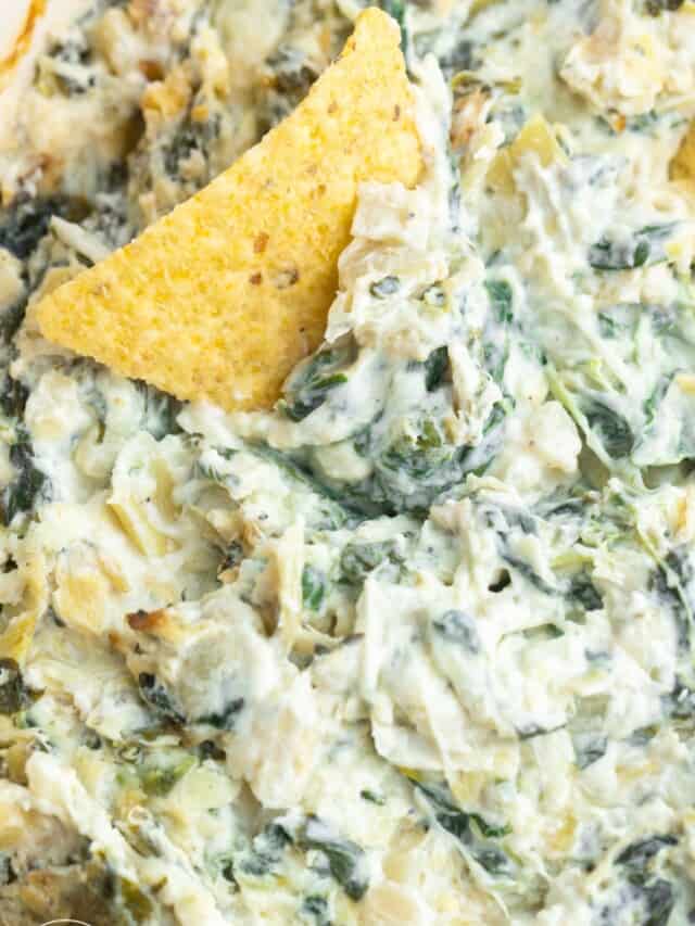 Close up shot of cheesy spinach artichoke dip and a tortilla chip