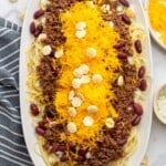 a large oval platter of cincinnati chili over spaghetti.