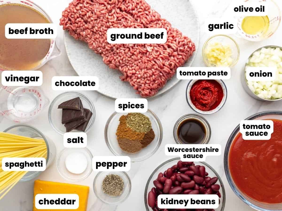 The ingredients needed to make cincinnati chili with beef, chocolate, tomatoes, beans, and spaghetti