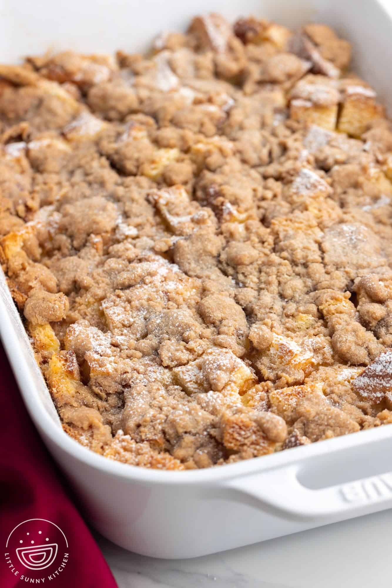 french toast casserole in a white rectangular dish topped with a sweet crumb