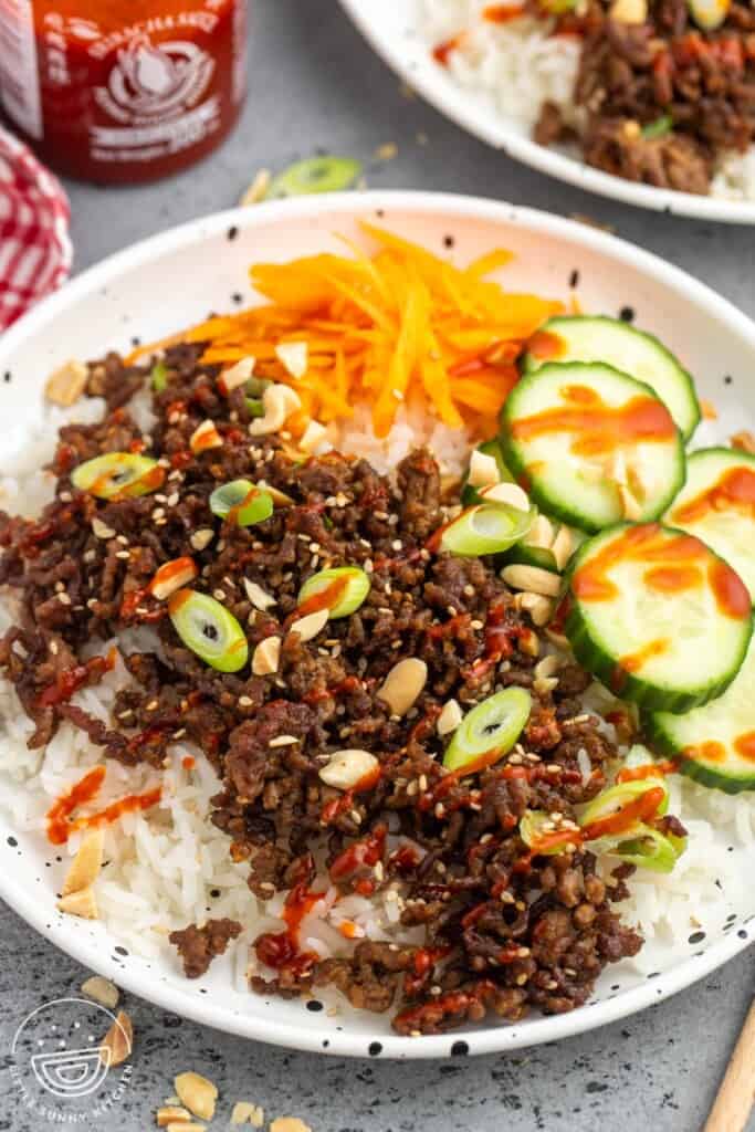 a korean rice bowl with ground beef and veggies.