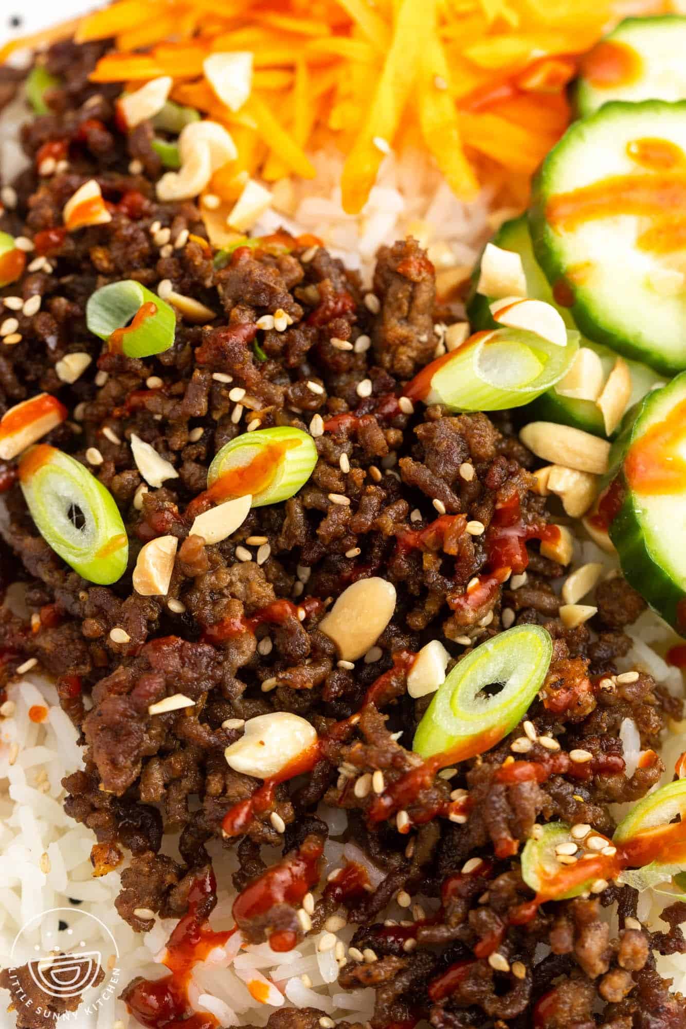 Closeup of korean beef bowl with rice, cucumbers, and ground seasoned meat