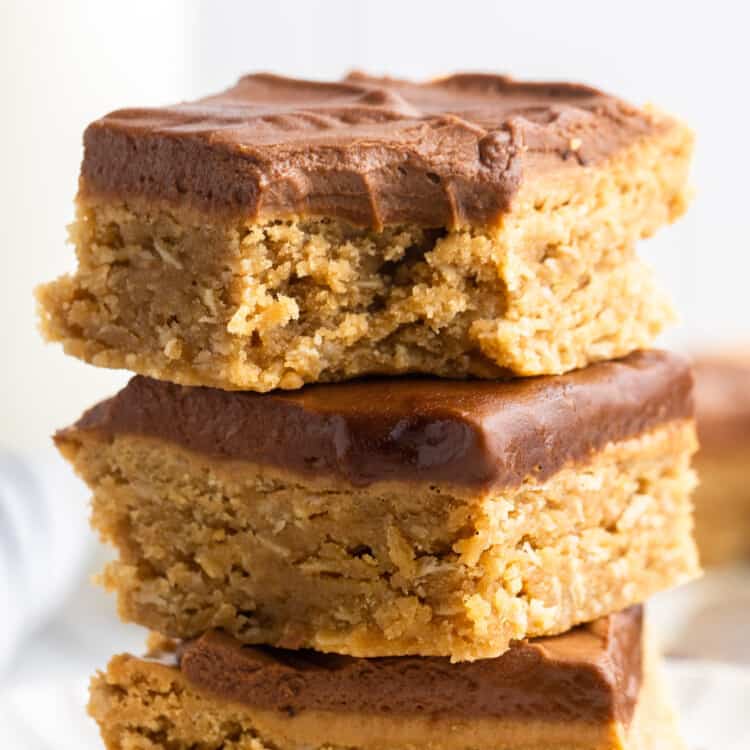three soft peanut butter bars with frosting, stacked on top of each other.