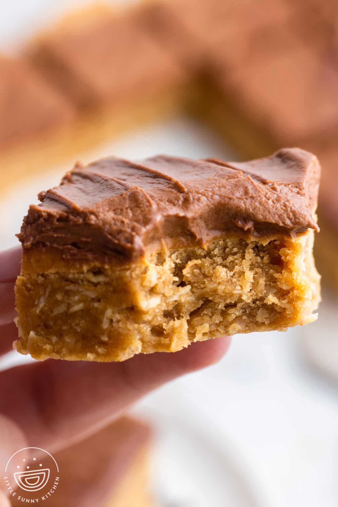 lunch lady peanut butter bar with chocolate frosting, held up with a bite taken.